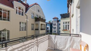 A balcony with a view of neighboring buildings, a chair, and a railing. - Sopocki Kredensik by Grand Apartments (Sopot)