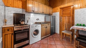 A compact kitchen with wooden cabinets, a stove, a washing machine, and a refrigerator. - Sopocki Kredensik by Grand Apartments (Sopot)