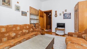 A living room with a sofa set, wooden cabinets, a television, and wall-mounted pictures. - Sopocki Kredensik by Grand Apartments (Sopot)