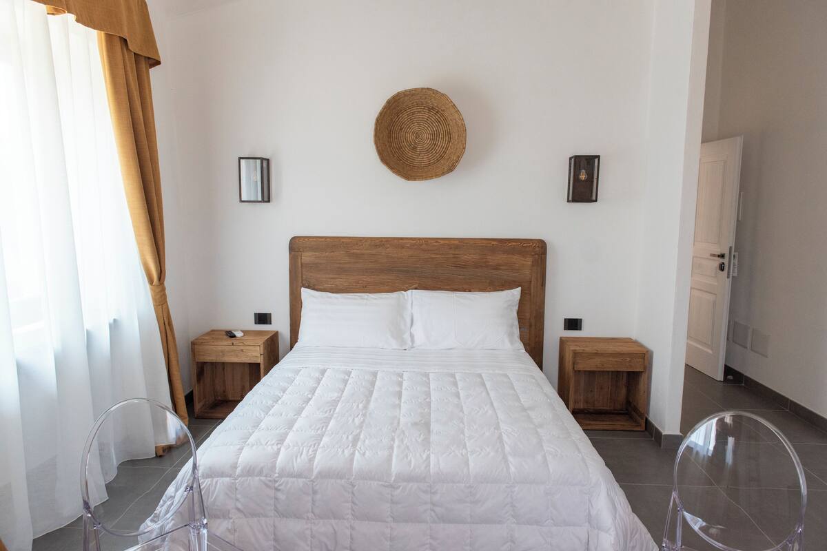 A neatly made bed with a wooden headboard, two bedside tables, and a woven wall hanging.