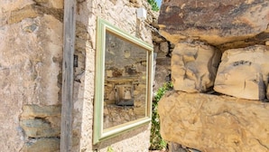 A stone wall with a wooden post and a framed mirror. - Albergo Rurale Casa Fois (Valledoria)