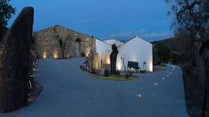 A building with a stone facade and a white tent-like structure in the center, surrounded by a paved area with lights. - Albergo Rurale Casa Fois (Valledoria)