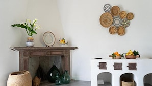 A room with a fireplace, a white table with baskets, and a wall decorated with woven plates. - Albergo Rurale Casa Fois (Valledoria)