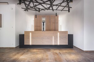 Una zona de recepción con un mostrador de madera, base negra e iluminación colgante.