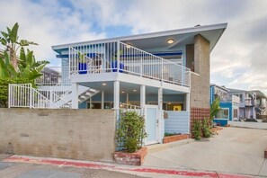 A modern two-story building with a balcony, a brick facade, and a clear sky.