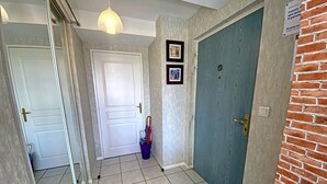 A hallway with a white door, a blue door, and a small bucket with umbrellas. - Penthouse in Lorient Center, 2 Bedrooms with Secure Parking (Lorient)