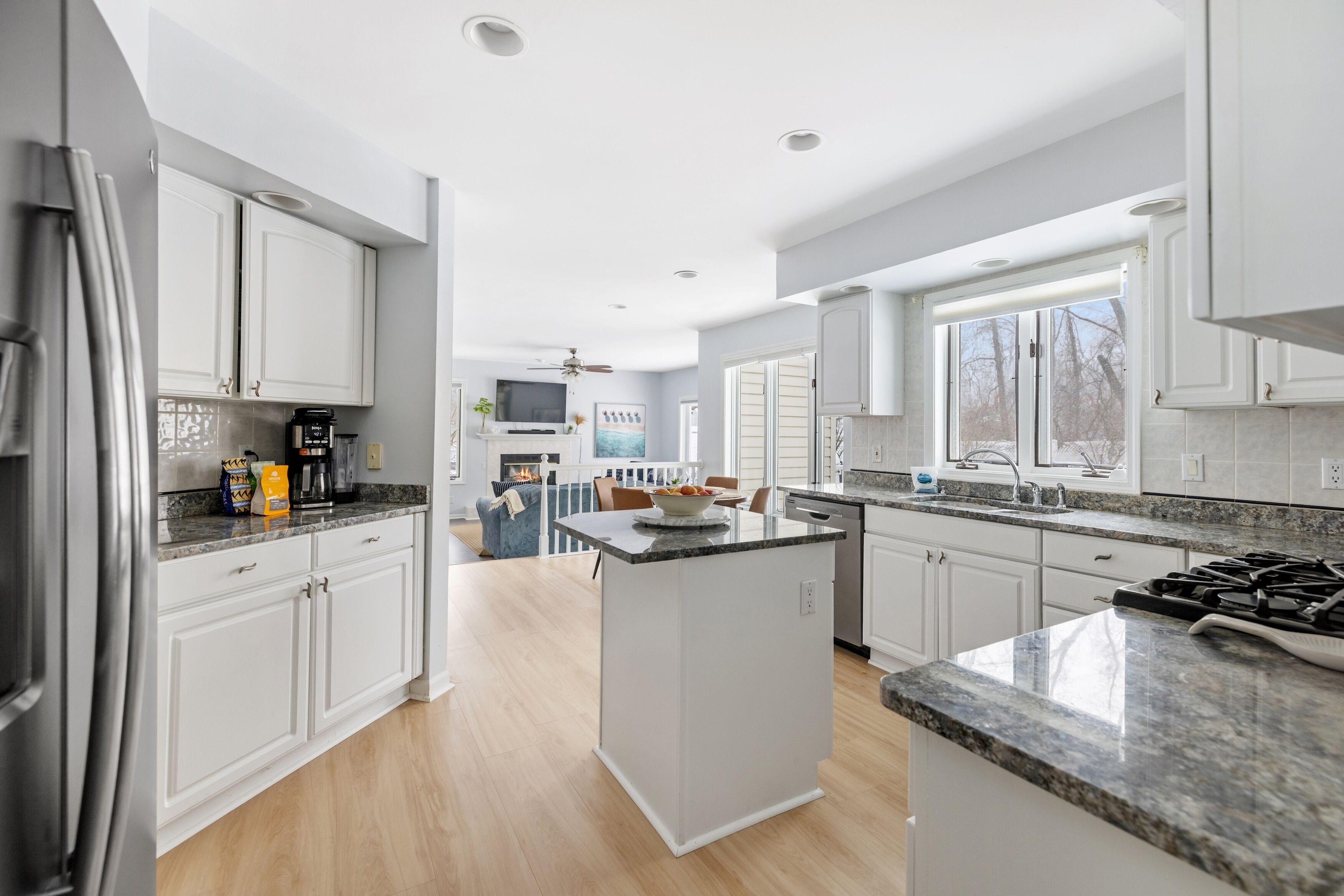 A modern kitchen with white cabinets, granite countertops, and a central island.