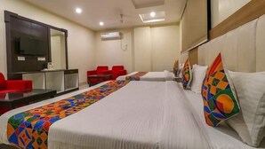 A hotel room with a large bed, a desk, a chair, and a television. - Hotel AGK (Haridwar)
