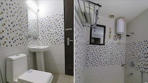A bathroom with a toilet, sink, and shower area, featuring mosaic tile walls and a white toilet. - Hotel AGK (Haridwar)