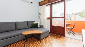 Una sala de estar moderna con un sofá gris, una mesa de centro de madera y un suelo de madera estampado.