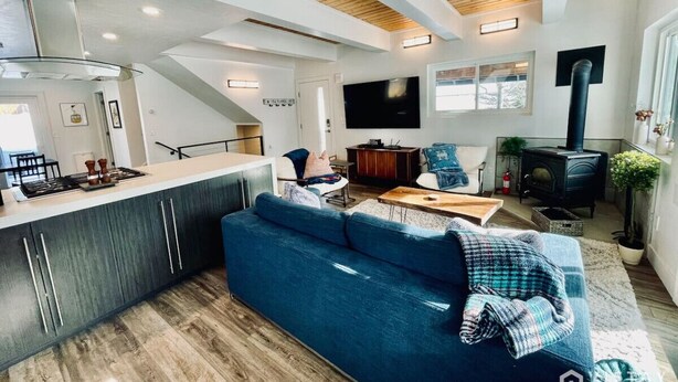 A modern living space with a kitchen, a blue sofa, a TV, and a wood-burning stove.