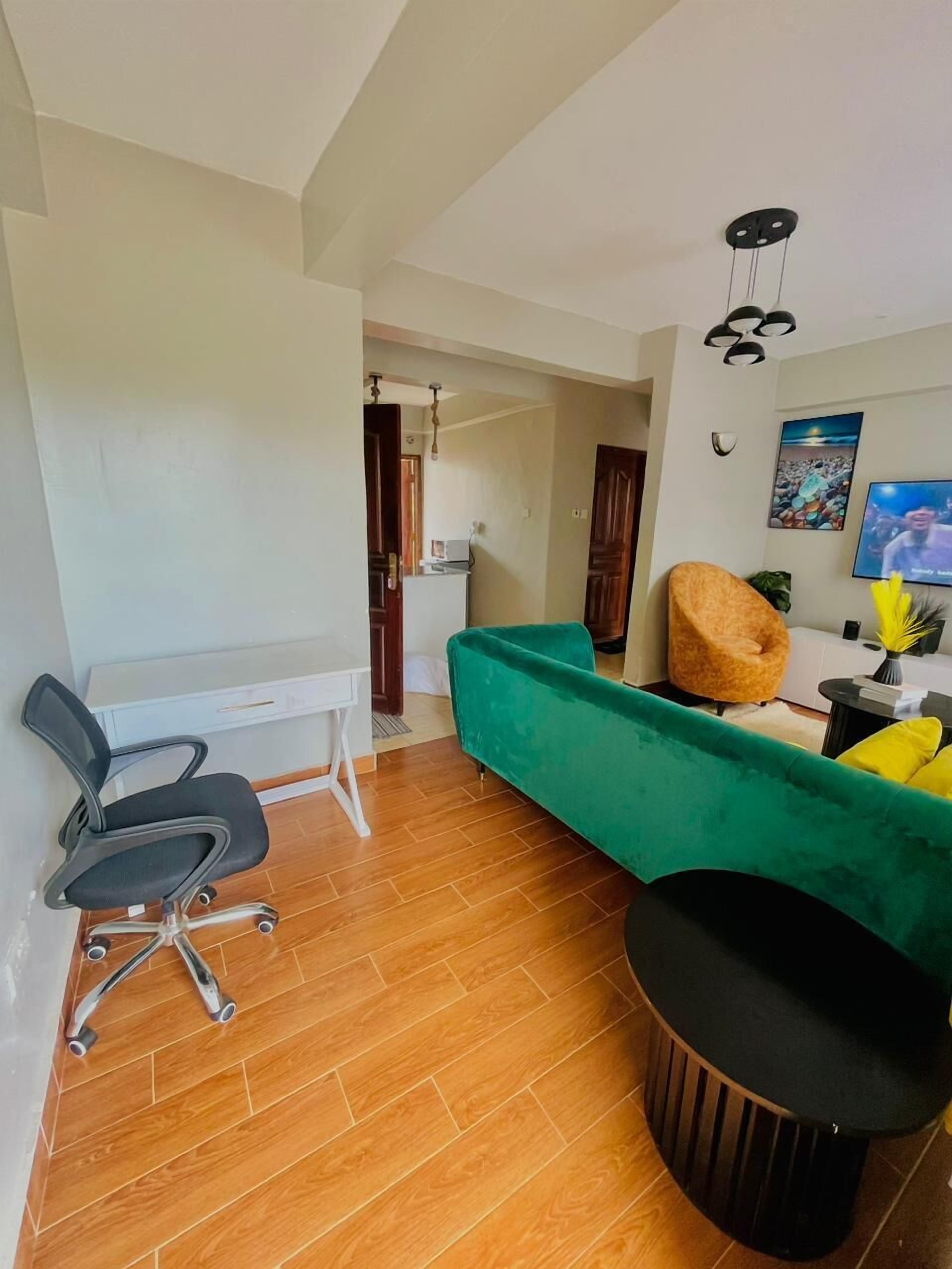 A compact living space with a desk, chair, sofa, and a television.