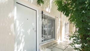 A residential building with a white door, barred windows, and a concrete pathway. - Cute and Convenient Studio in Athens (Athens)