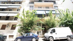 A multi-story building with balconies, a parked car, and a van. - Cute and Convenient Studio in Athens (Athens)