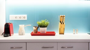 A kitchen counter with a coffee maker, a kettle, a potted plant, a knife block, and a red tray. - Cute and Convenient Studio in Athens (Athens)