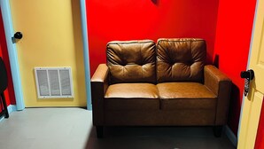 A room with a brown leather sofa, a yellow door, and a red wall.