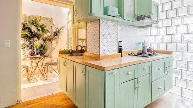 A modern kitchen with green cabinets, a wooden countertop, and a built-in stove. - Cozy Condesa (Mexico City)