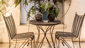 A round metal table with two metal chairs, surrounded by potted plants. - Cozy Condesa (Mexico City)