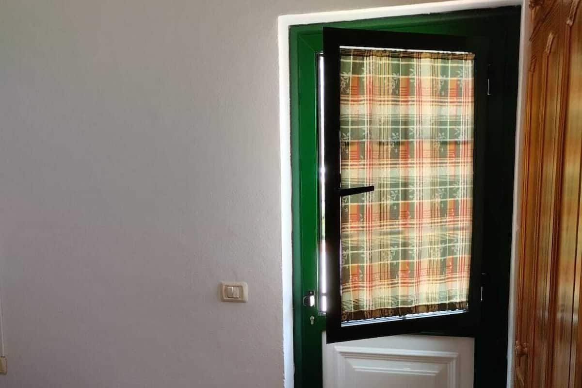 A room with a closed door, a bed with a white bedspread, and a tiled floor.