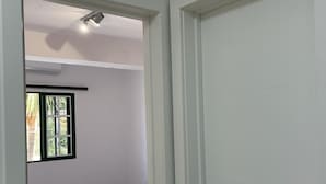 A bedroom with two beds, a window with a view, and a door leading to another room. - Apartamentos Casa Rural Guadá (Valle Gran Rey)