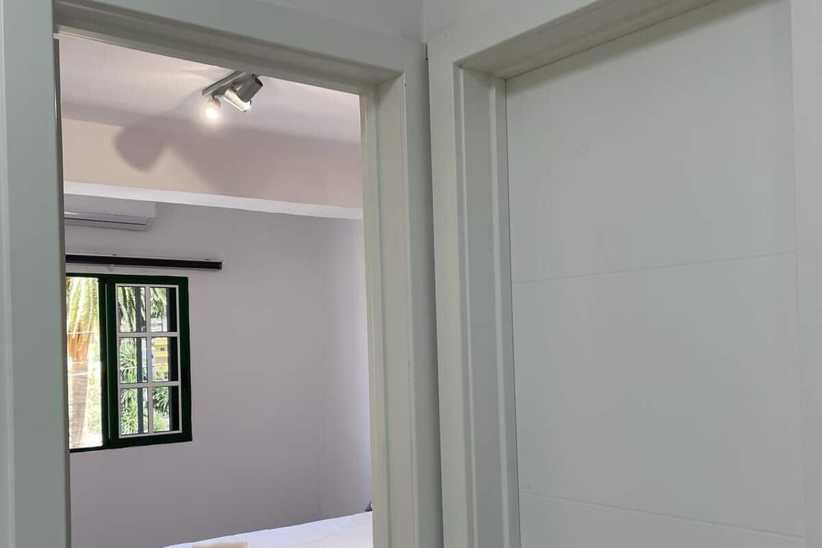 A bedroom with two beds, a window with a view, and a door leading to another room.