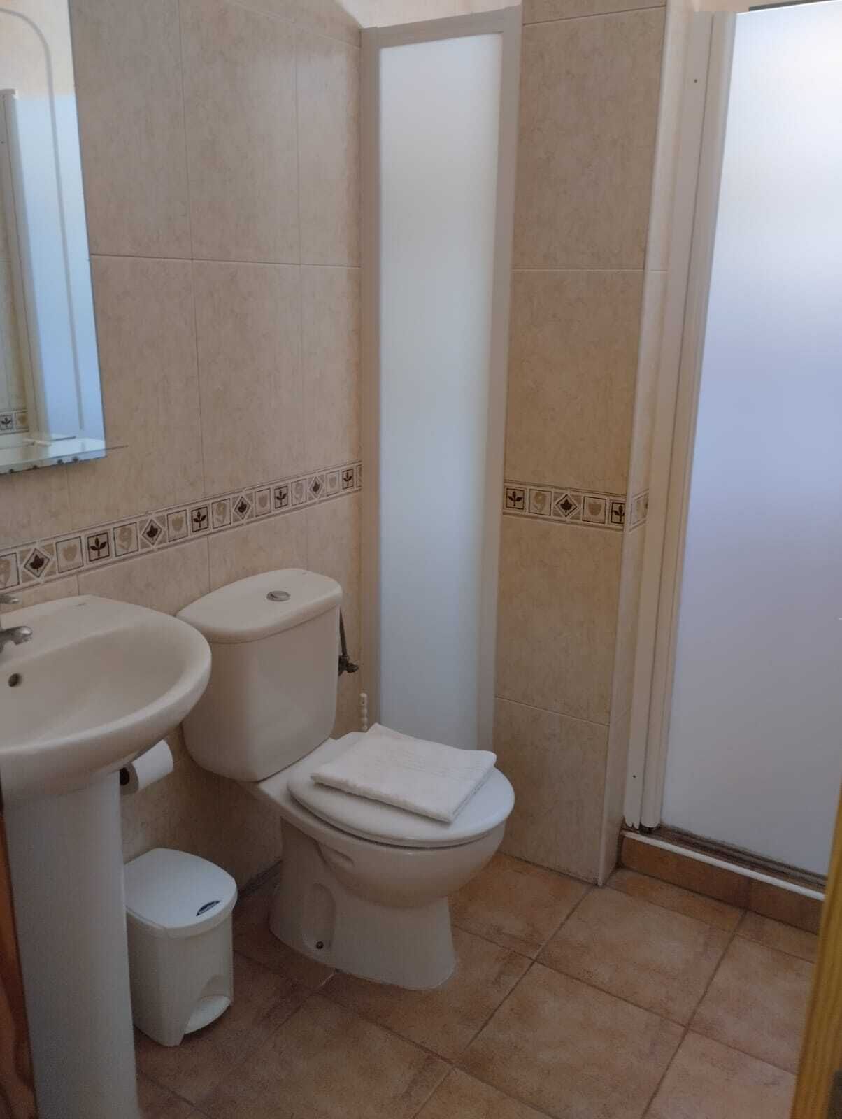 Un bagno con un lavandino, due servizi igienici e uno specchio.
