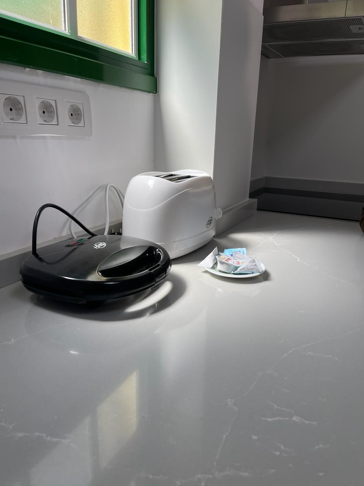 A kitchen with a countertop, a toaster, and a robotic vacuum cleaner.