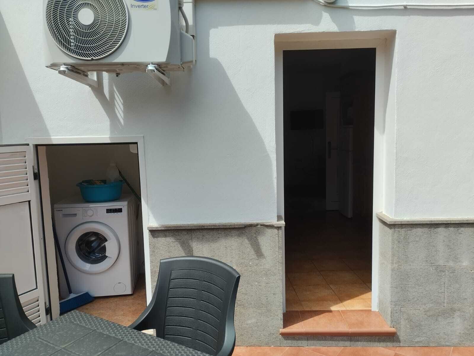 Ein Waschbereich mit Waschmaschine, Ventilator und Stuhl.