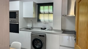 A compact kitchen with a built-in washing machine, a microwave, and a toaster. - Apartamentos Casa Rural Guadá (Valle Gran Rey)