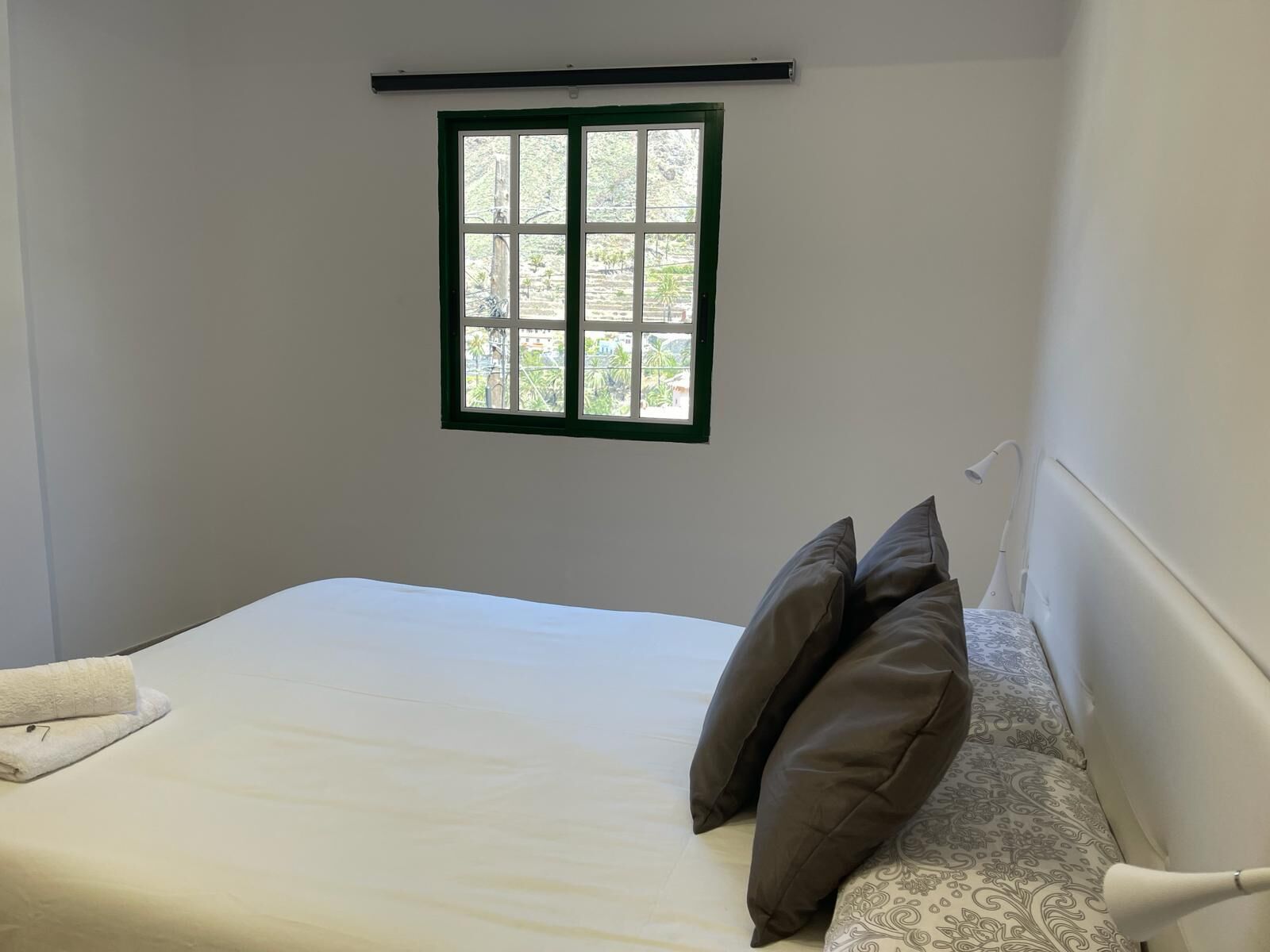 A bedroom with a bed, a window, and a bedside lamp.