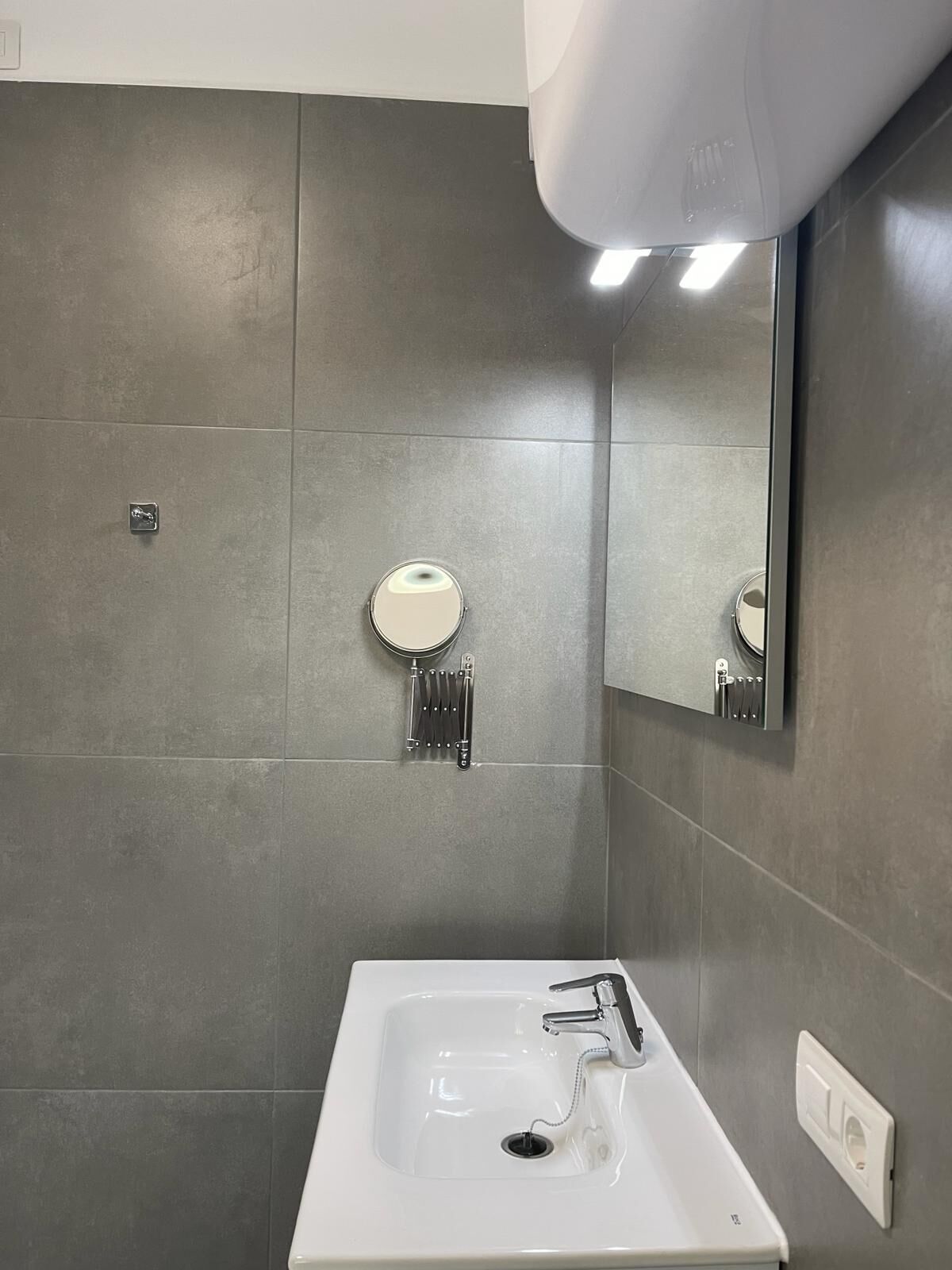Une salle de bain moderne avec un lavabo blanc, un miroir et un porte-serviettes.