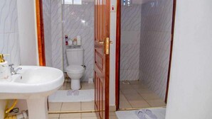 A bathroom with a white sink, toilet, and shower area. - Lux Suites Truna Executive Homes Kisii (Kisii)
