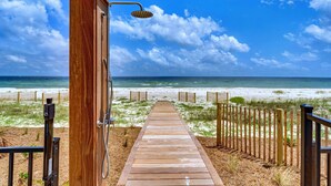 A wooden pathway leading to a beach with a wooden structure on the left.