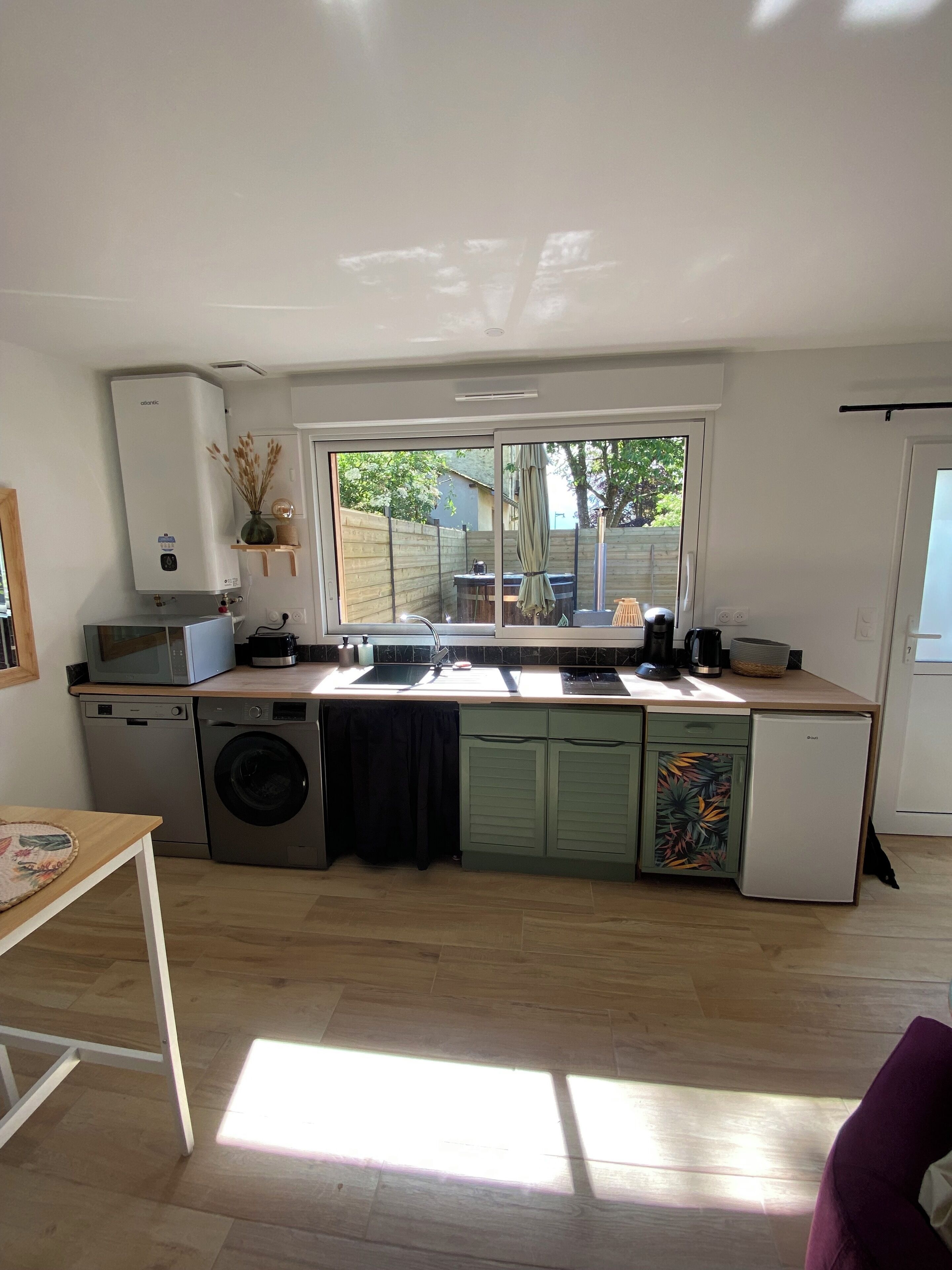 Een compacte keuken met een ingebouwde wasmachine en droger, een magnetron en een koelkast.