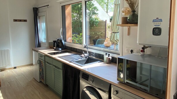 A compact kitchen with a built-in washing machine, a sink, and a window providing natural light.