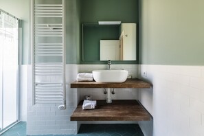 A bathroom with a white sink, wooden shelves, a towel rack, and a mirror. - Easylife - Studio with balcony in Risorgimento (Milano)