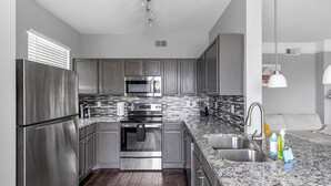 A modern kitchen with stainless steel appliances, a granite countertop, and a built-in oven.