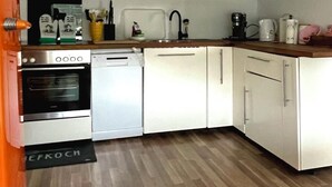 Une cuisine compacte avec des meubles blancs, un four encastré, un lave-vaisselle et un four à micro-ondes.