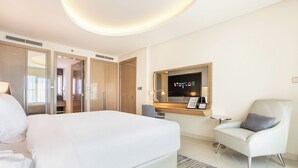 A modern hotel room with a large bed, a TV mounted on the wall, a seating area with a chair, and a wardrobe. - Staycae Holiday Homes - DAMAC Towers (Dubai)