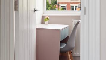 A small, private office space with a desk and chair, a potted plant, and a window with a view of buildings outside.