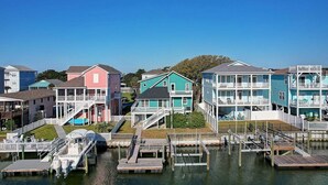 A waterfront property with multiple colorful houses, docks, and boats. - Relax in this charming home in Holden Beach featuring 3 bedrooms. (Holden Beach)