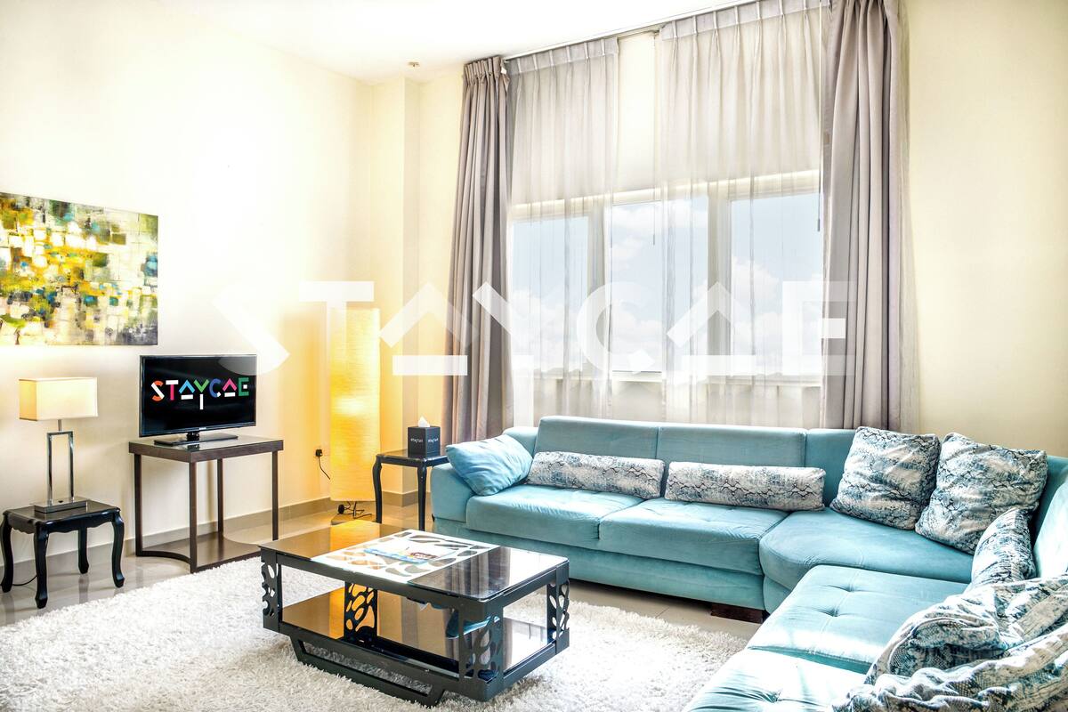 A living room with a sofa, a coffee table, a TV on a stand, and a painting on the wall.