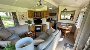 Ein gemütlicher Wohnbereich mit Sofa, Esstisch, Fernseher und Küchenzeile.