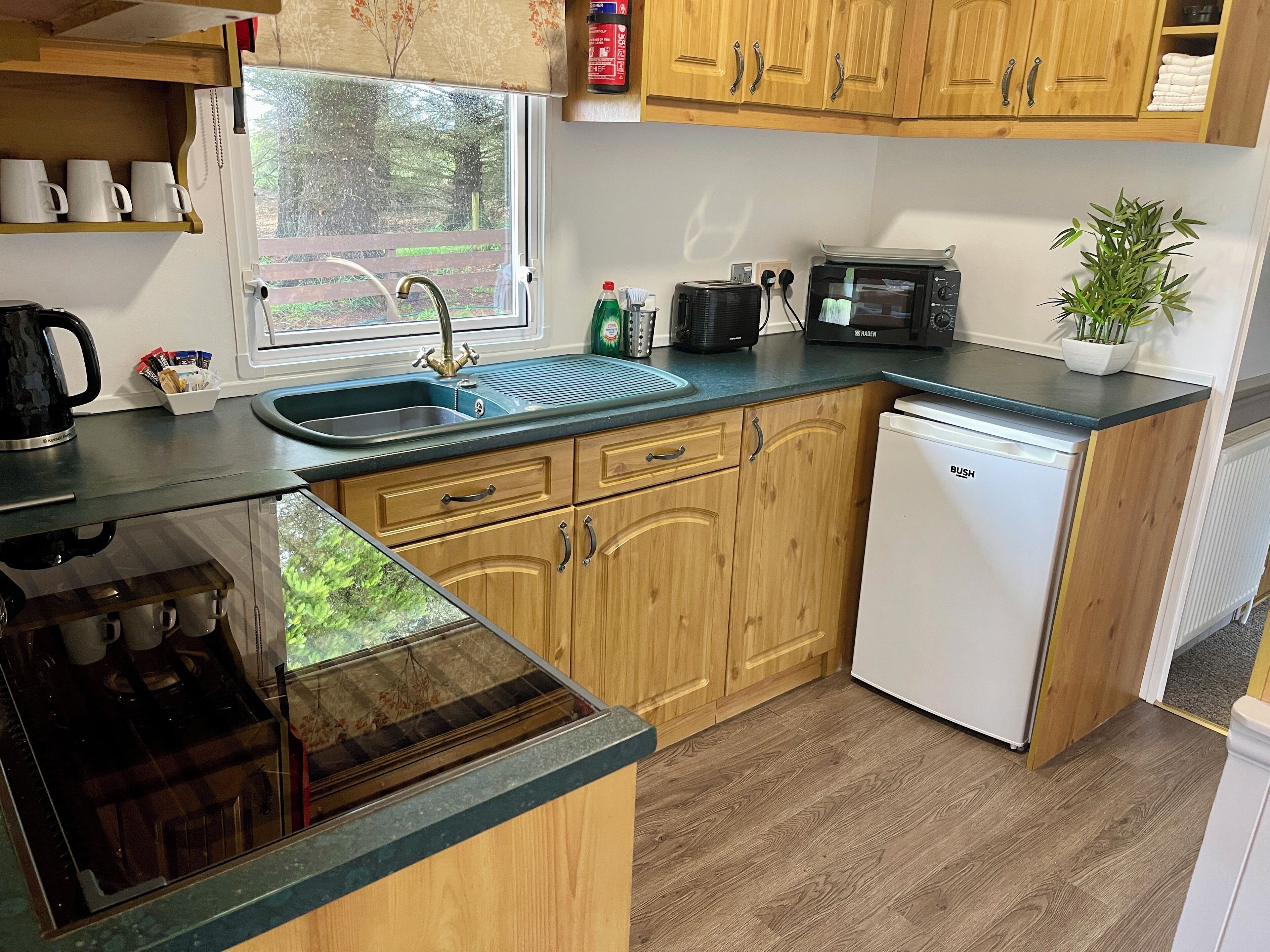 A compact kitchen with wooden cabinets, a sink, a microwave, and a dishwasher.