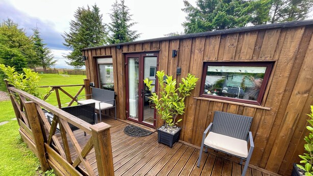 Eine Holzterrasse mit Sitzgelegenheiten, einer Tür und einem Fenster.