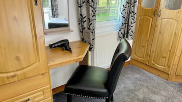 Una habitación con un escritorio de madera, una silla de cuero negro y un armario con puertas de espejo.