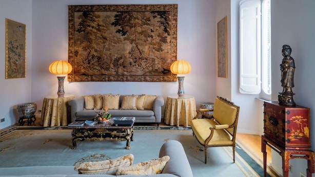 A traditional room with a sofa, armchairs, a coffee table, and a large tapestry on the wall. - Apartment located on the main floor of a historic building in the center of Rome (Roma)