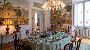 A dining room with a round table set for a meal, surrounded by chairs. - Apartment located on the main floor of a historic building in the center of Rome (Roma)