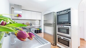 A modern kitchen with stainless steel appliances, a built-in oven, and a glass display case with flowers. - Apartment located on the main floor of a historic building in the center of Rome (Roma)