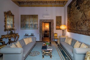 Um quarto com dois sofás, uma mesa de centro, uma pintura grande e um candelabro.
